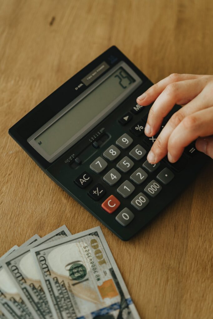 Calculadora preta sendo utilizada para fazer cálculos financeiros ao lado das finanças de um indivíduo representando o uso da matemática financeira.